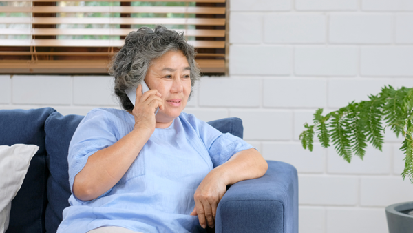Older female talking phone while sitting in home living room