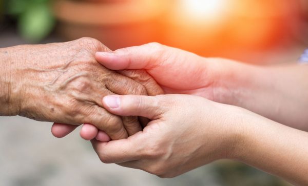 Older adult holding hands with younger adult to show support for them being protected from elder abuse.