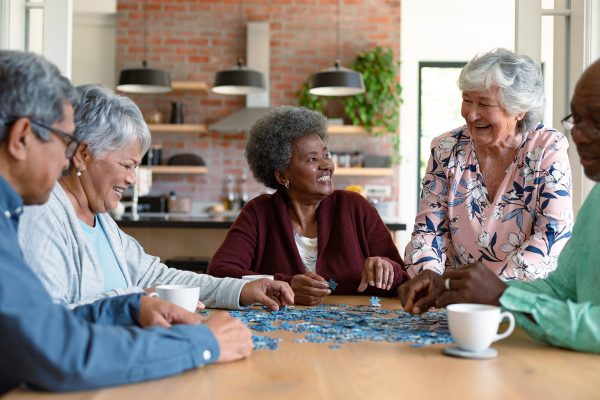 Older adults putting together a puzzle as they chat over coffee