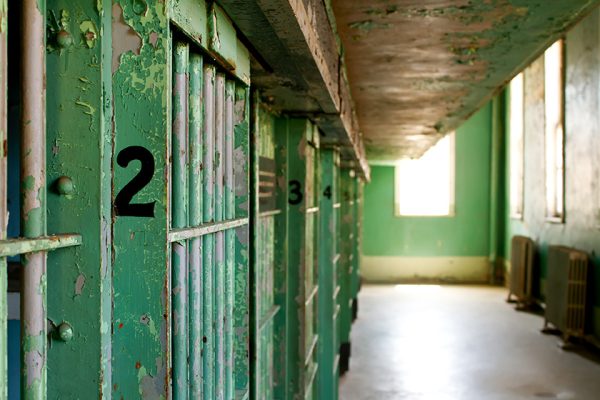 Prison area where inmates sleep, a green paint covers the wall and a number 2 designating a cell is highlighted, light purs in from a window on the right