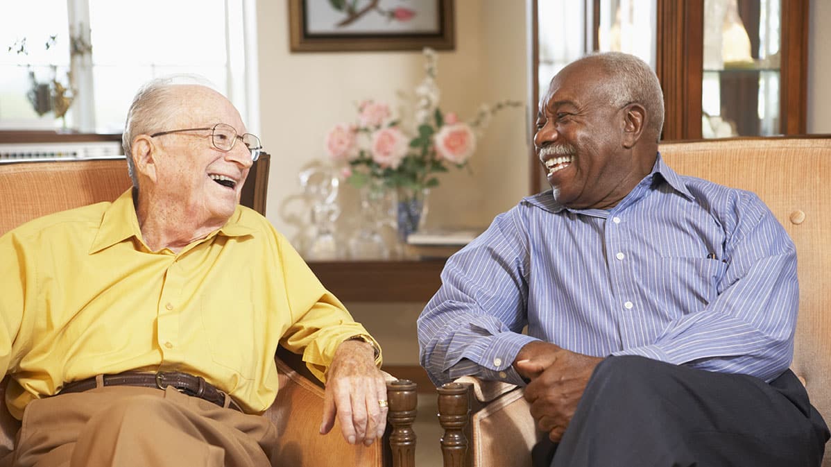 Two older adults chatting in a living room engaged in good conversation