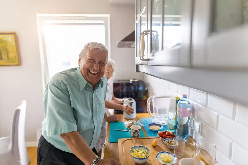older gentleman in kitchen cooking lunch with his wife