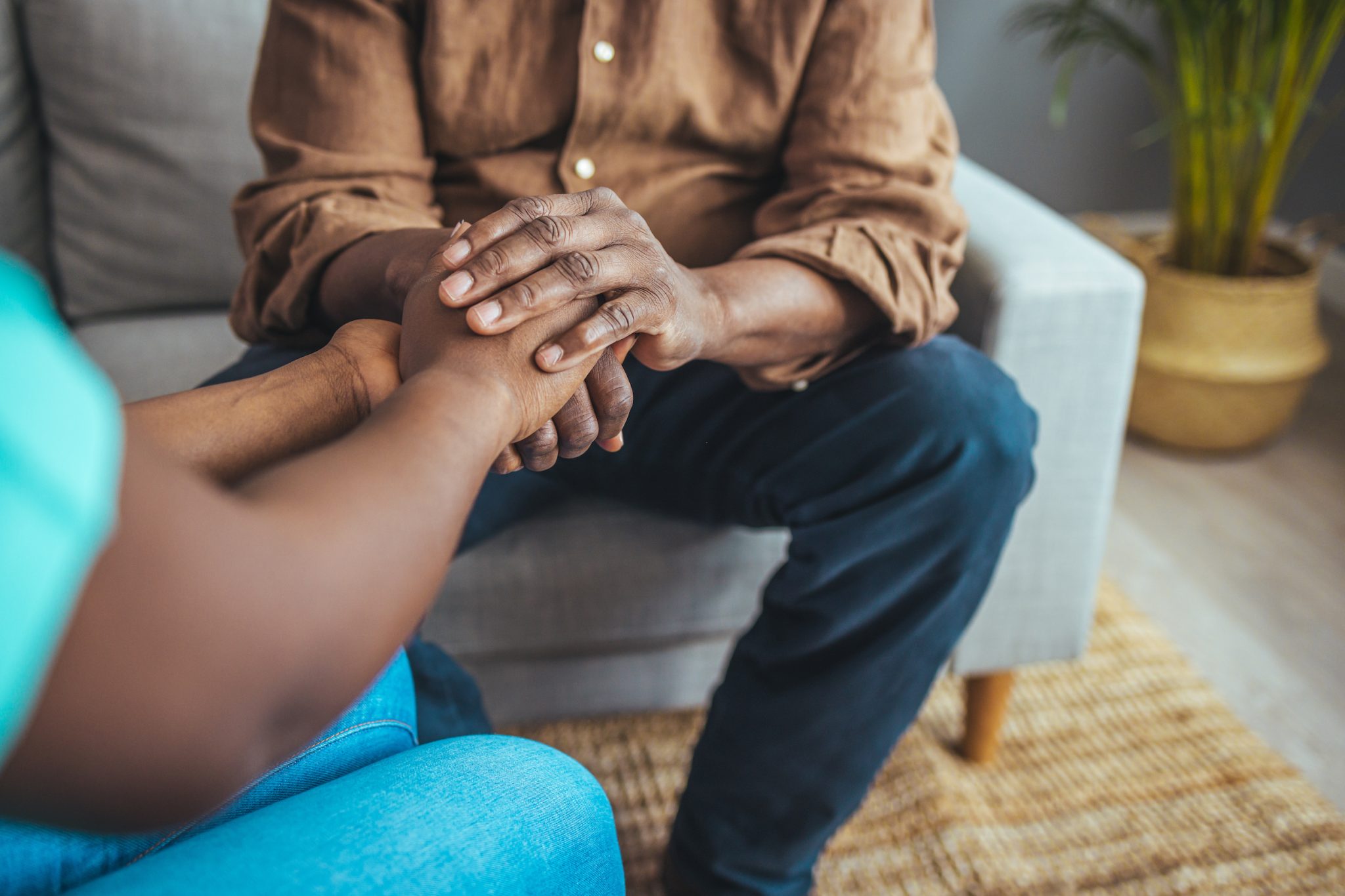 Closeup shot of a younger caregiver holding hands with an older adult.