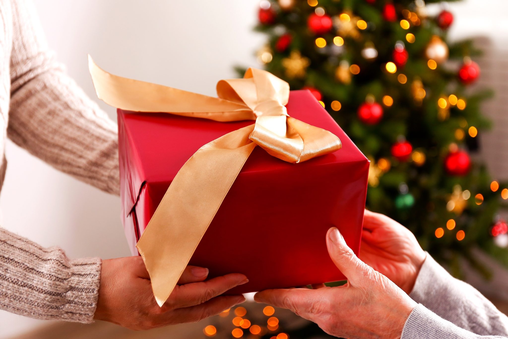 Hands exchanging a wrapped gift during the holidays, reflecting appreciation and the spirit of giving within the Michigan caregiving community.