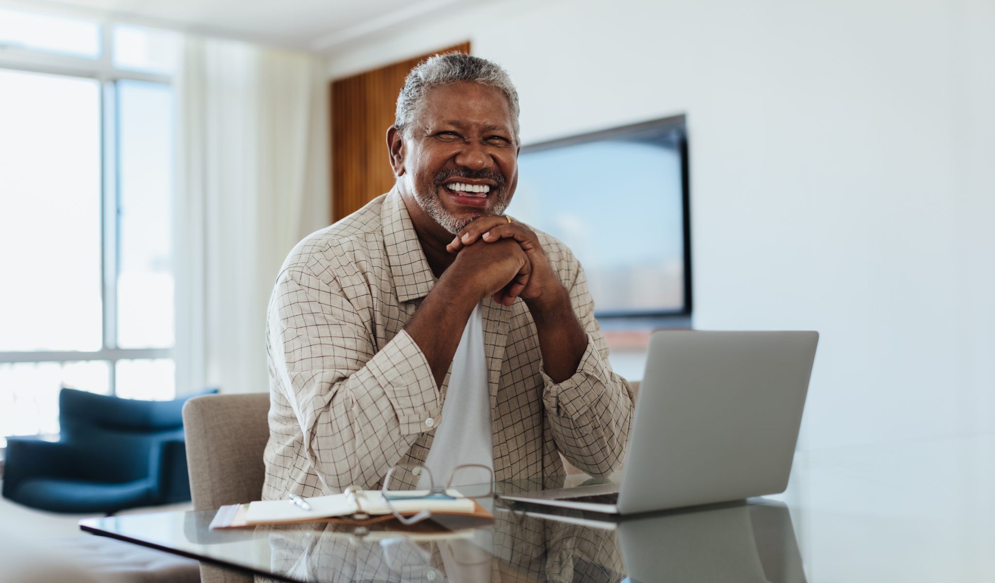 Cheerful senior man writing a letter to his legislator from his laptop.