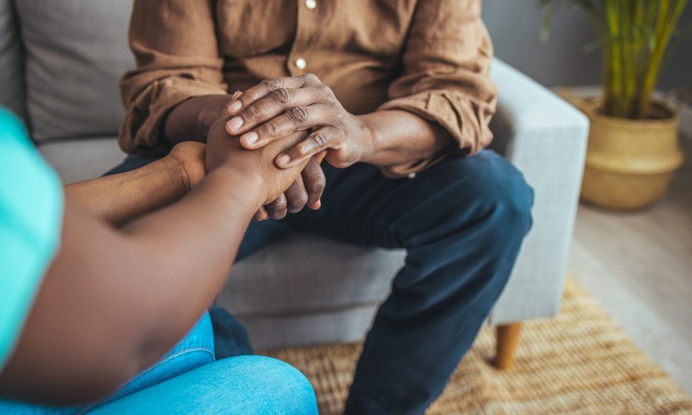 Closeup shot of a younger caregiver holding hands with an older adult.