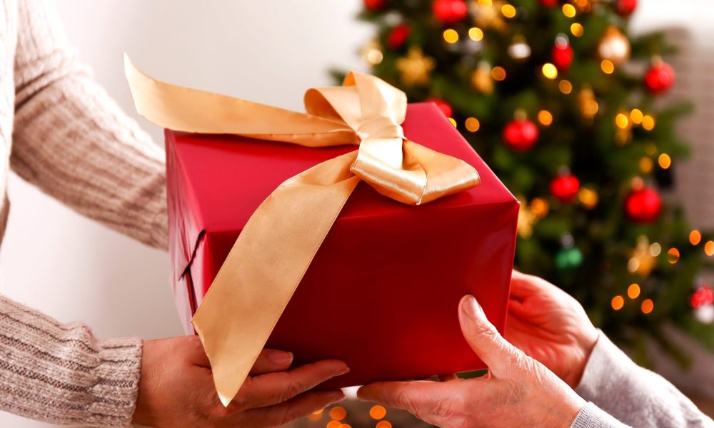 Hands exchanging a wrapped gift during the holidays, reflecting appreciation and the spirit of giving within the Michigan caregiving community.